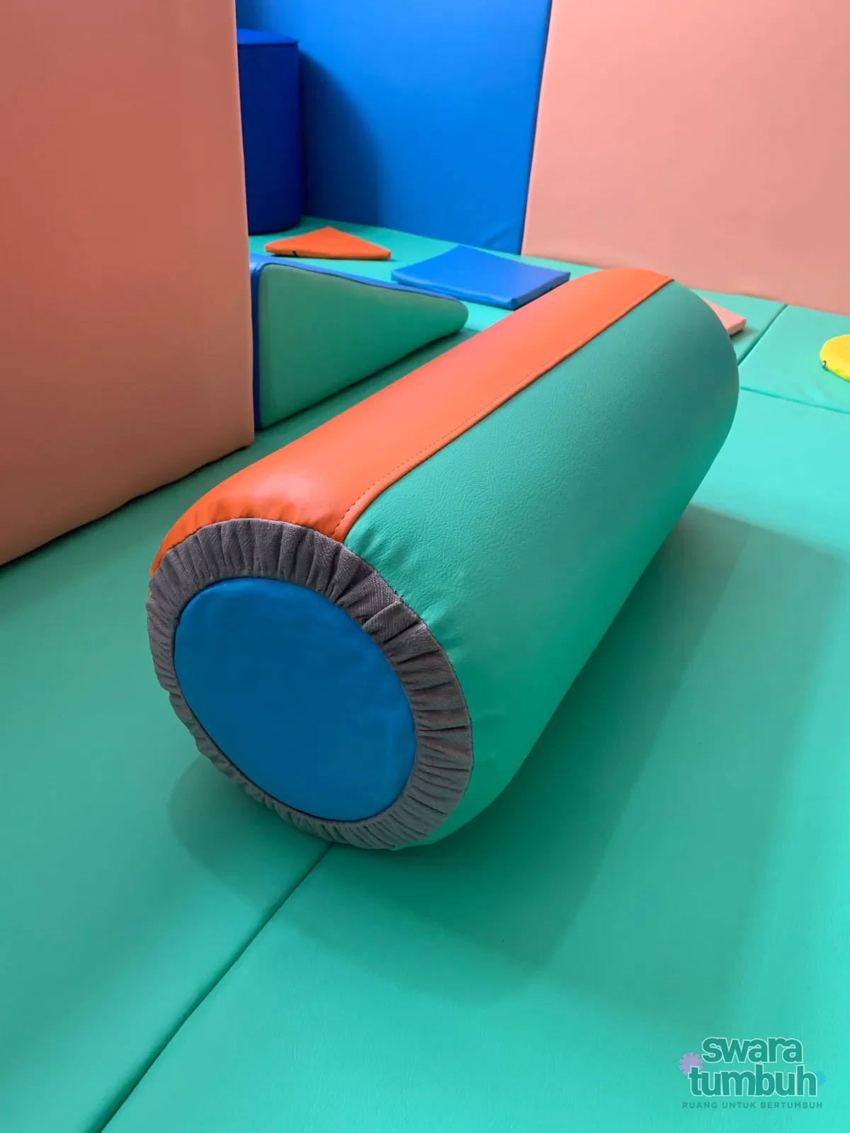 Bolster terapi anak berbentuk silinder dengan pelapis hijau, jingga, dan biru