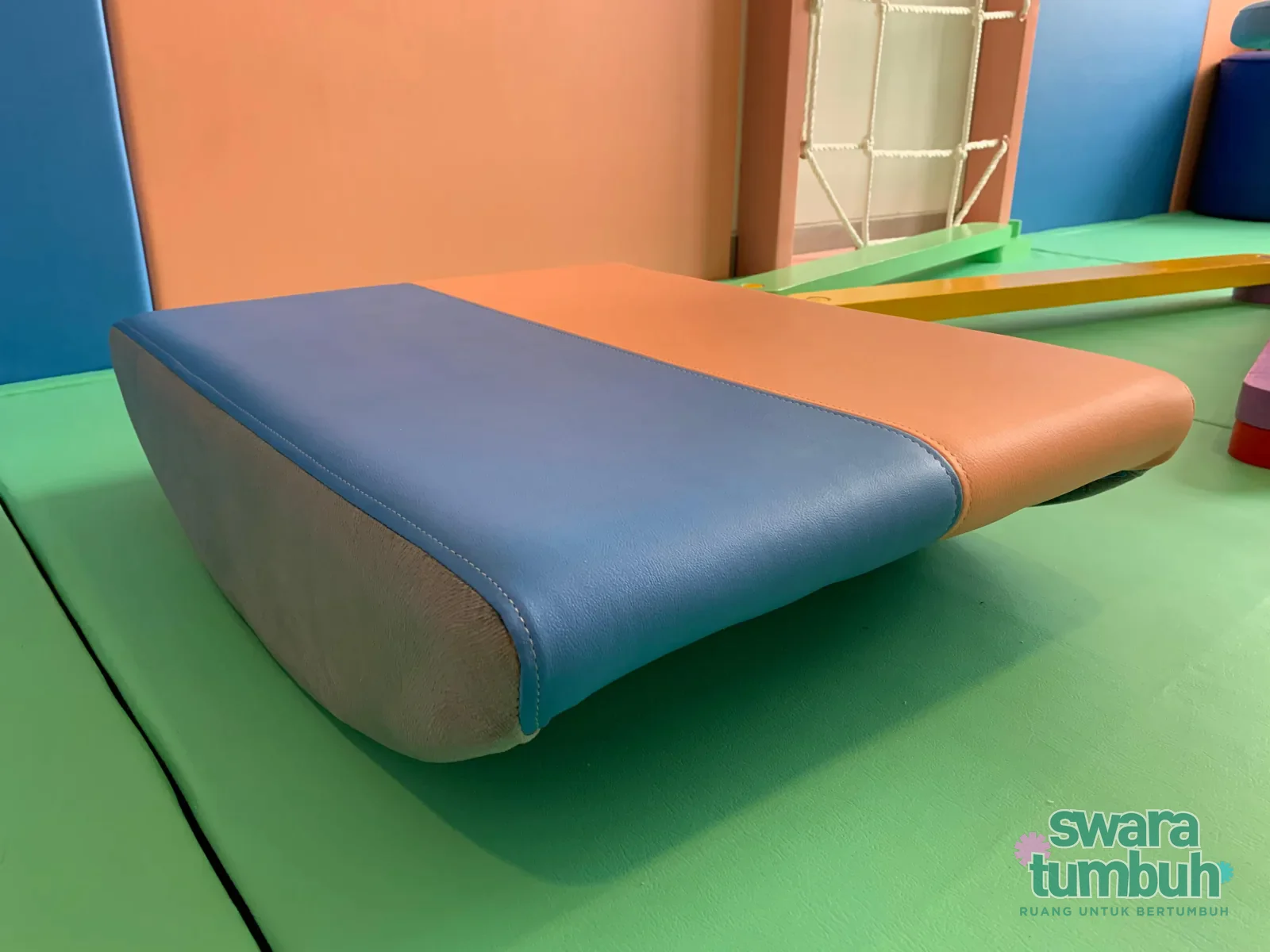Vestibular board terapi anak dengan pelapis biru, peach, dan abu-abu